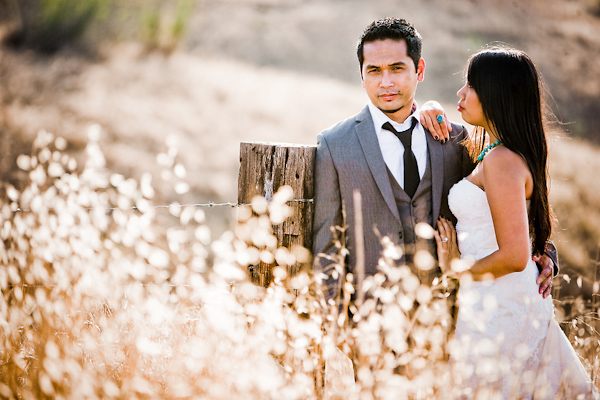 Bride and groom standing next to barbed wire fence in the